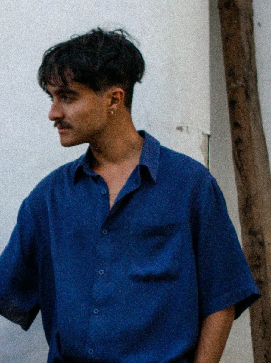 Andrés Vázquez Marqués, de pie junto a un muro encalado, con camisa azul.